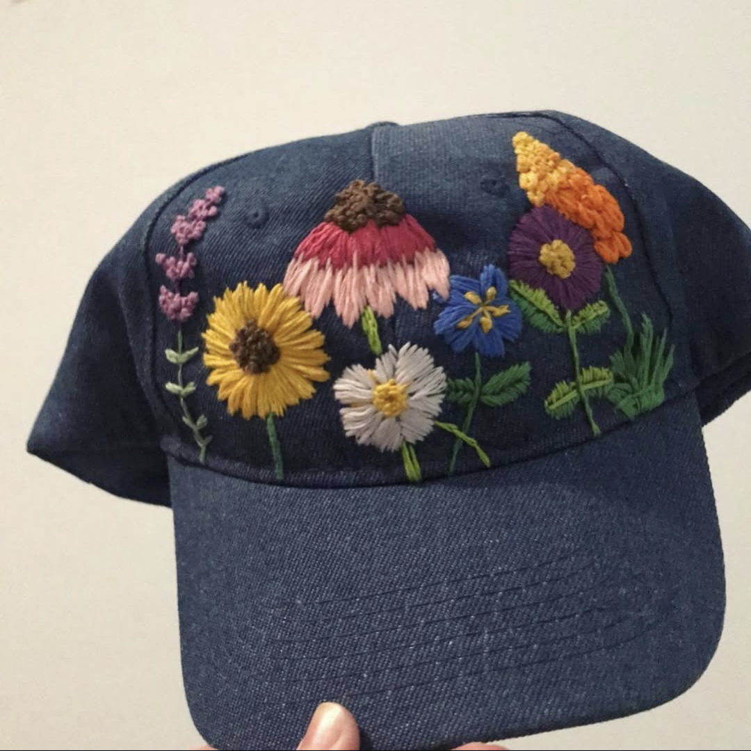 Various flowers embroidered on to a dark blue denim baseball cap.