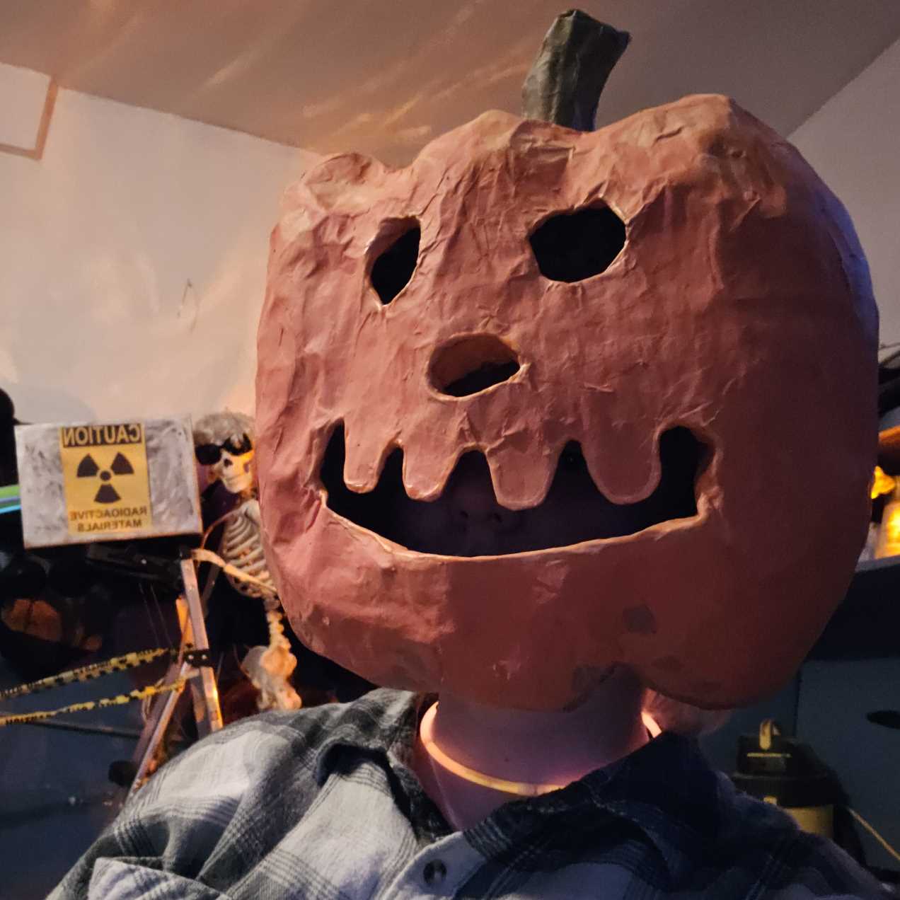 Papier-mâché pumpkin head on a person. It is carved into a smile.